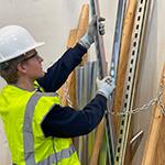 Hunter in a hard hat, safety vest and gloves selecting a piece of metal from a pile.